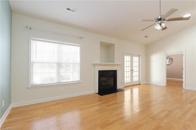 unfurnished living room featuring a ceiling fan, visible vents, light wood-style flooring, a fireplace with flush hearth, and vaulted ceiling