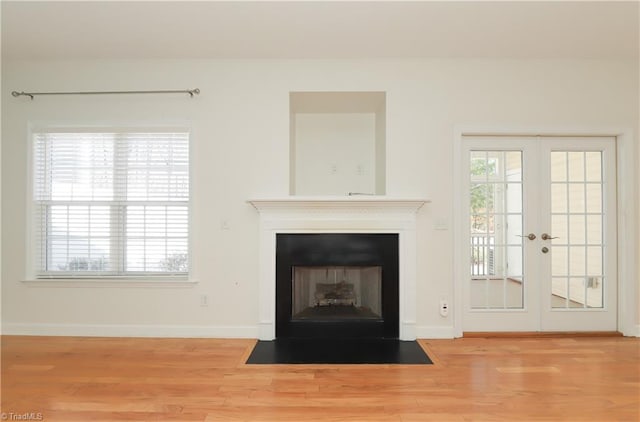 unfurnished living room featuring french doors, plenty of natural light, and wood finished floors