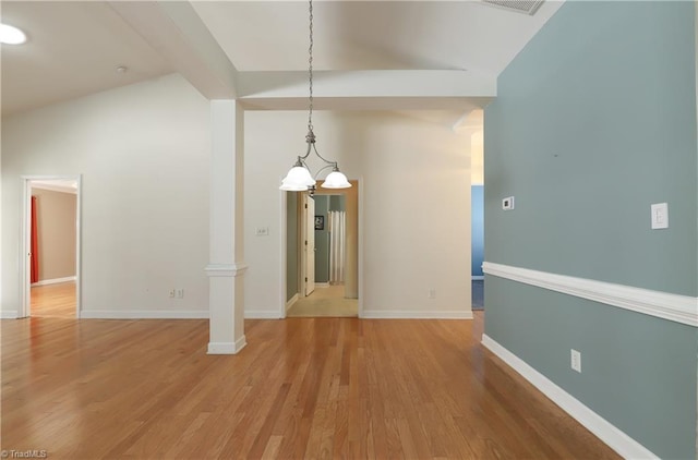 unfurnished dining area with baseboards, light wood-style floors, vaulted ceiling, and ornate columns