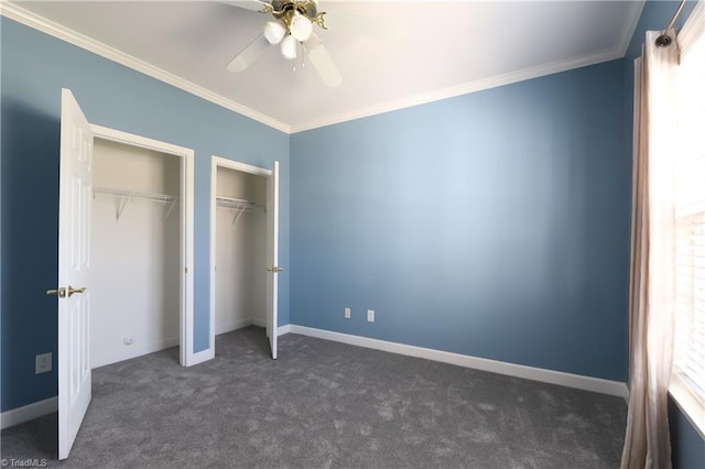 unfurnished bedroom with dark carpet, multiple closets, and crown molding