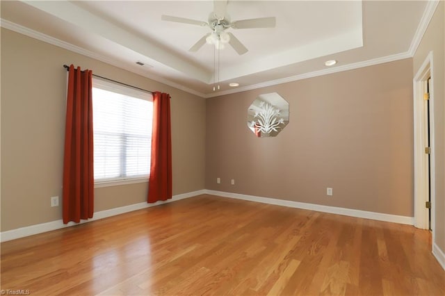 spare room with a ceiling fan, a tray ceiling, light wood-style floors, and baseboards