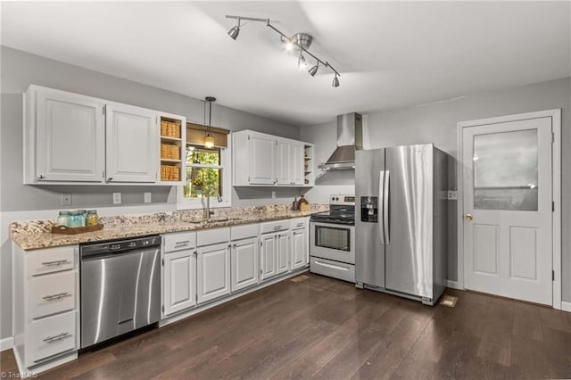 kitchen featuring appliances with stainless steel finishes, white cabinetry, wall chimney exhaust hood, decorative light fixtures, and dark wood-type flooring