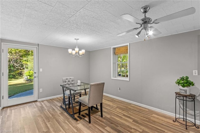 dining room with a wealth of natural light, hardwood / wood-style flooring, and ceiling fan with notable chandelier