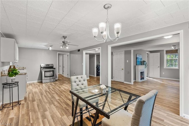 dining space featuring light hardwood / wood-style flooring, ceiling fan with notable chandelier, and washer / clothes dryer