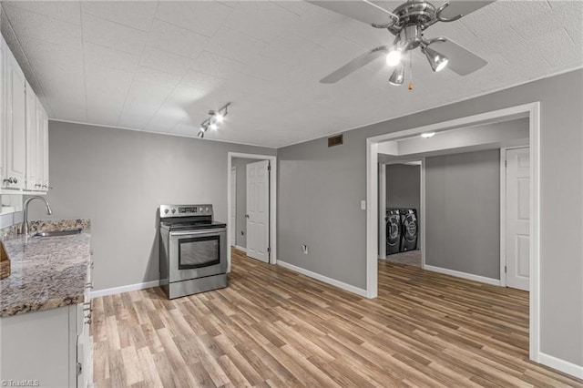 kitchen with light hardwood / wood-style floors, stainless steel electric range, sink, and white cabinets