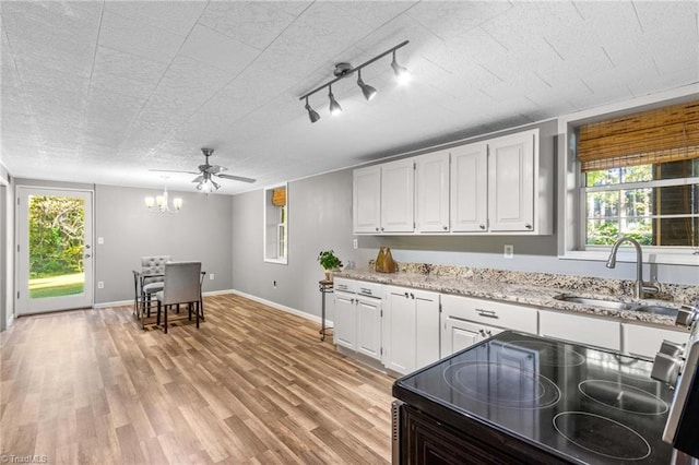 kitchen with sink, white cabinetry, ceiling fan with notable chandelier, and light wood-type flooring