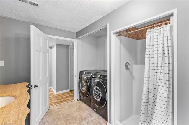 clothes washing area with washing machine and dryer and light hardwood / wood-style floors