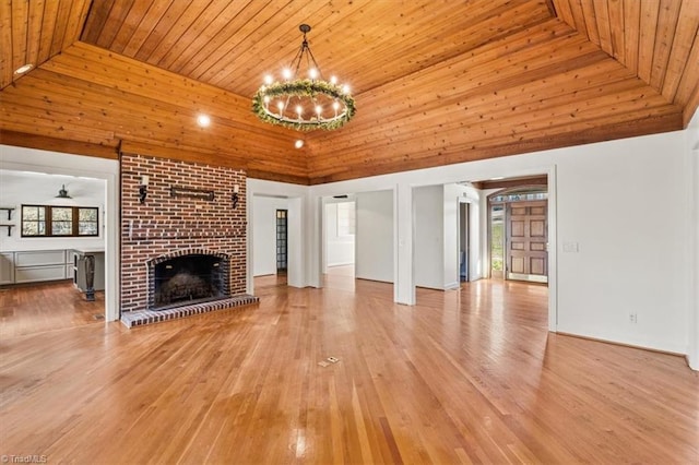 unfurnished living room featuring ceiling fan with notable chandelier, wooden ceiling, light wood-type flooring, and a fireplace