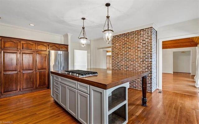 kitchen featuring decorative light fixtures, wooden counters, a center island, gray cabinetry, and stainless steel appliances