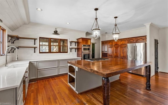 kitchen featuring a center island, decorative light fixtures, stainless steel appliances, sink, and vaulted ceiling