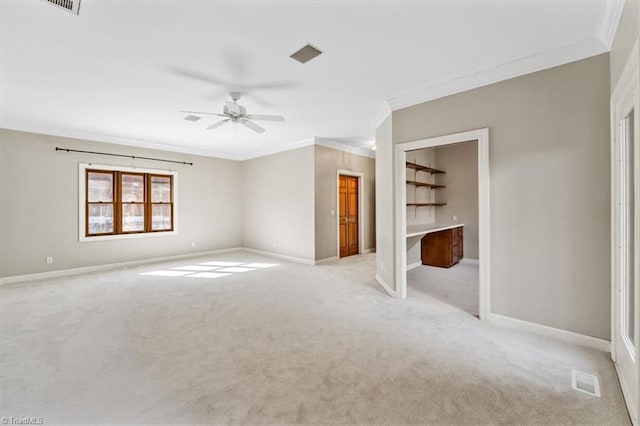 unfurnished room featuring ceiling fan, ornamental molding, built in desk, and light colored carpet