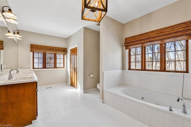 bathroom with toilet, vanity, tile patterned floors, and tiled tub