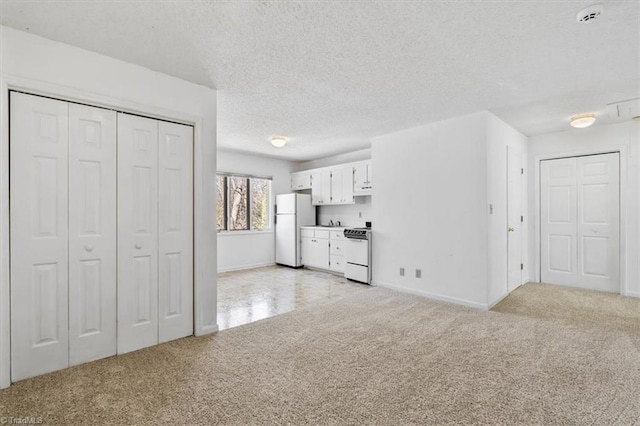 unfurnished living room featuring light colored carpet and a textured ceiling