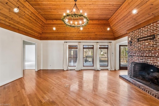 unfurnished living room with wood ceiling, hardwood / wood-style floors, a high ceiling, a fireplace, and a chandelier