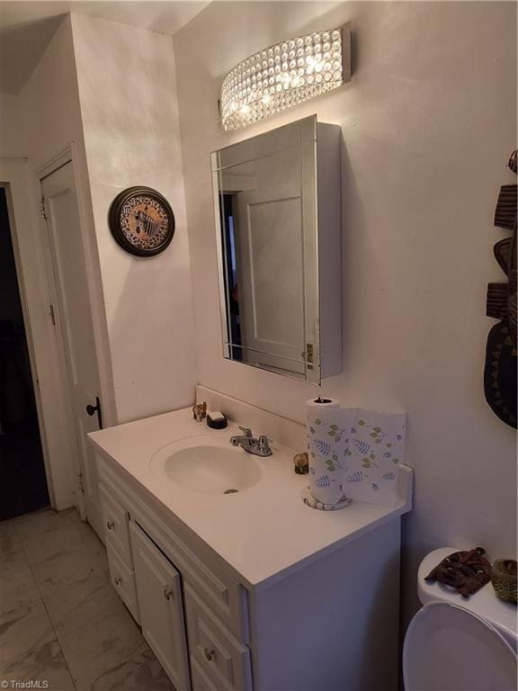 bathroom featuring an inviting chandelier, vanity, and toilet