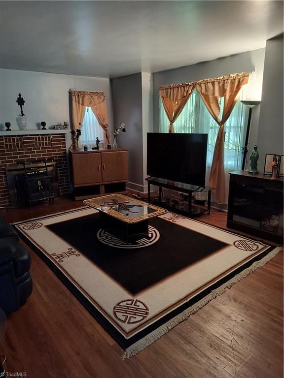 living room featuring wood-type flooring, a wealth of natural light, and a wood stove