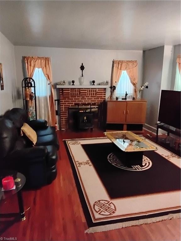 living room featuring dark hardwood / wood-style flooring, a healthy amount of sunlight, and a brick fireplace