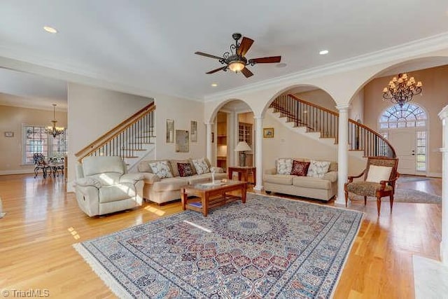 living room with arched walkways, stairway, and light wood-style floors