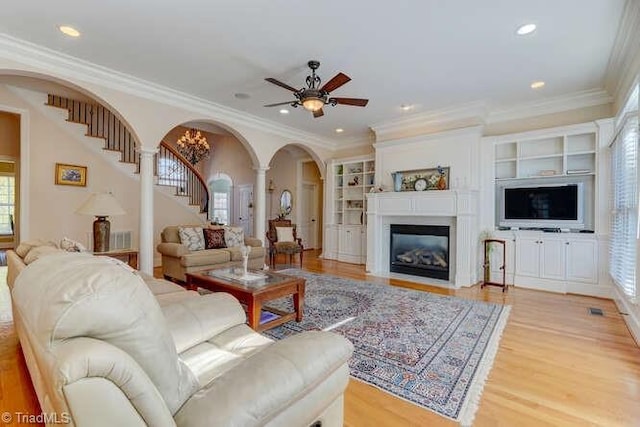 living area with stairs, light wood finished floors, and ornamental molding