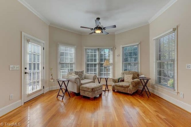 living area with baseboards, a ceiling fan, light wood-style floors, and ornamental molding