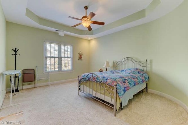 bedroom featuring a tray ceiling, a ceiling fan, baseboards, and carpet floors