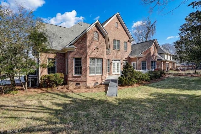 back of house with brick siding and a yard