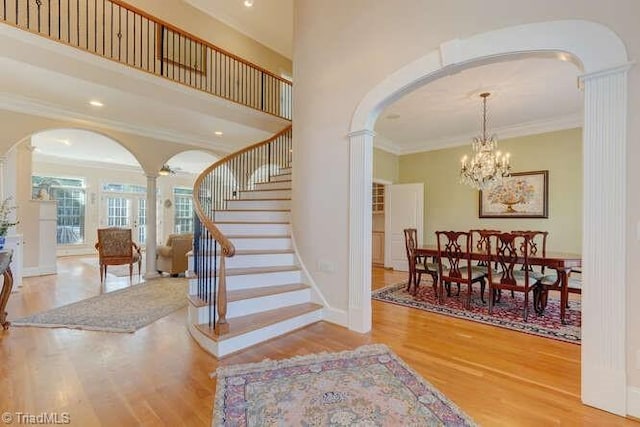 entryway featuring arched walkways, ornate columns, and wood finished floors