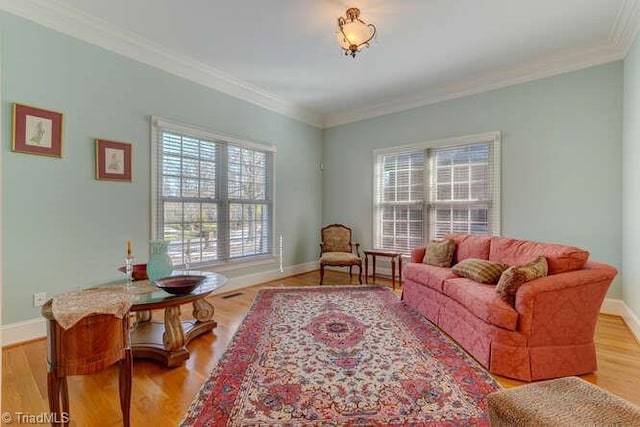 living area featuring ornamental molding, baseboards, and wood finished floors