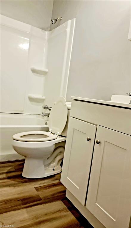 2410 Madre Pl, Greensboro, NC 27406 - bathroom with toilet, wood finished floors, vanity, and  shower combination