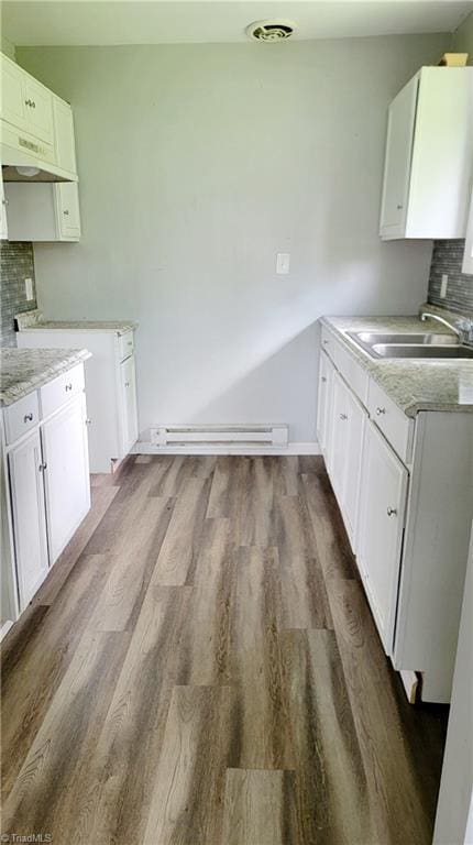 2410 Madre Pl, Greensboro, NC 27406 - kitchen featuring a sink, baseboard heating, under cabinet range hood, tasteful backsplash, and dark wood finished floors