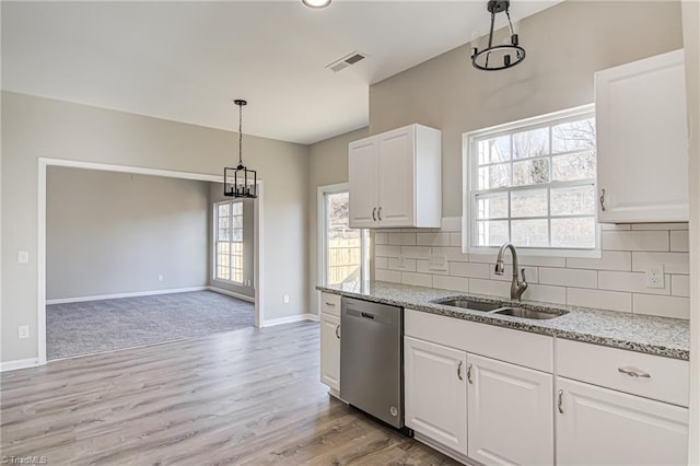 kitchen with pendant lighting, backsplash, white cabinets, sink, and stainless steel dishwasher