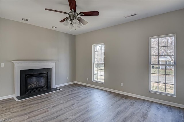 unfurnished living room featuring light wood-type flooring, ceiling fan, and a healthy amount of sunlight