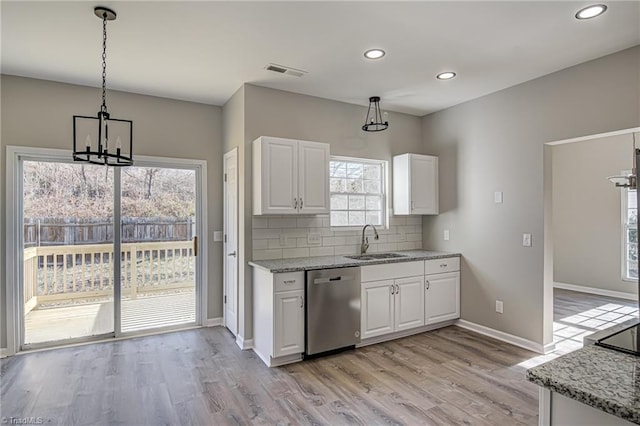 kitchen with stainless steel dishwasher, white cabinets, sink, and hanging light fixtures