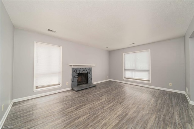 unfurnished living room with wood finished floors, baseboards, a fireplace, and a textured ceiling