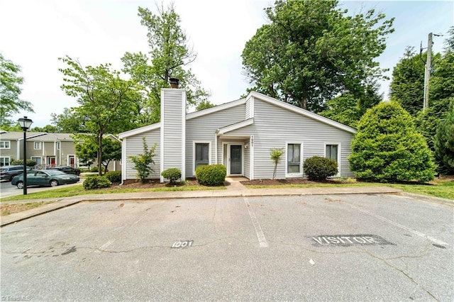 mid-century inspired home featuring uncovered parking and a chimney