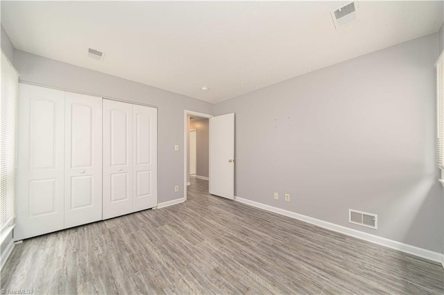 unfurnished bedroom featuring baseboards, wood finished floors, and a closet