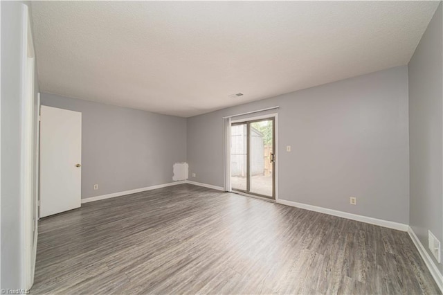 unfurnished room with wood finished floors, baseboards, and a textured ceiling