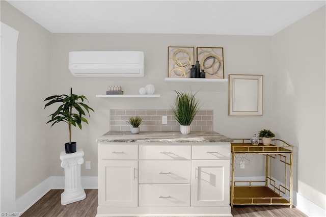 bar featuring dark wood-type flooring, white cabinetry, backsplash, light stone countertops, and an AC wall unit