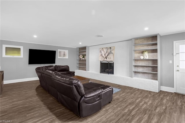 living room featuring dark wood-type flooring, crown molding, and built in features