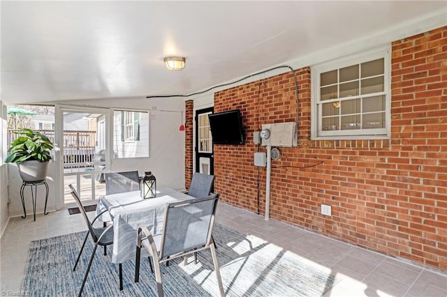 tiled dining space featuring brick wall