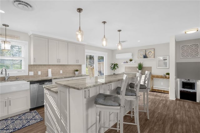 kitchen with white cabinetry, decorative light fixtures, stainless steel dishwasher, and a kitchen island