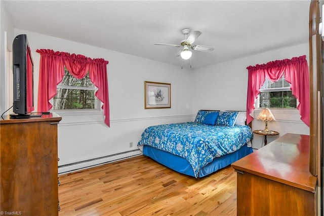 bedroom with hardwood / wood-style floors, baseboard heating, and ceiling fan