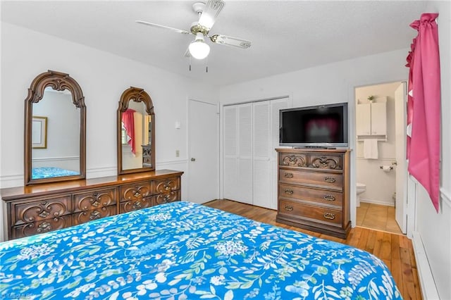 bedroom featuring connected bathroom, ceiling fan, baseboard heating, hardwood / wood-style floors, and a closet