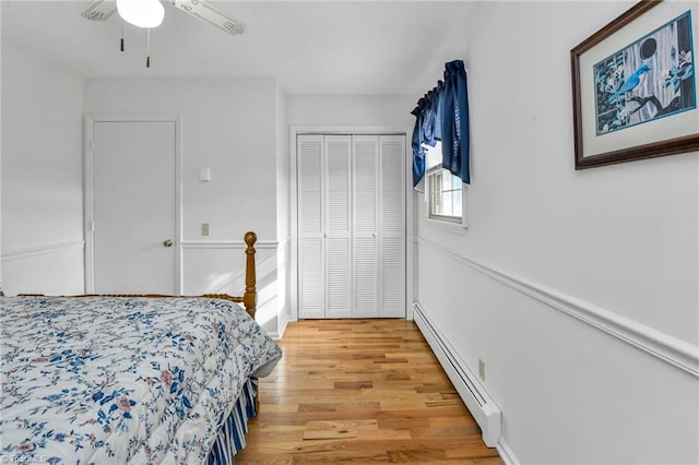 bedroom featuring ceiling fan, a closet, light hardwood / wood-style flooring, and a baseboard heating unit