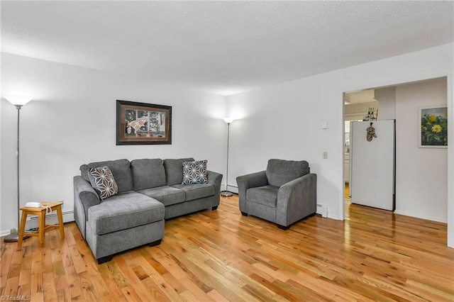 living room featuring a textured ceiling, light wood-type flooring, and a baseboard radiator