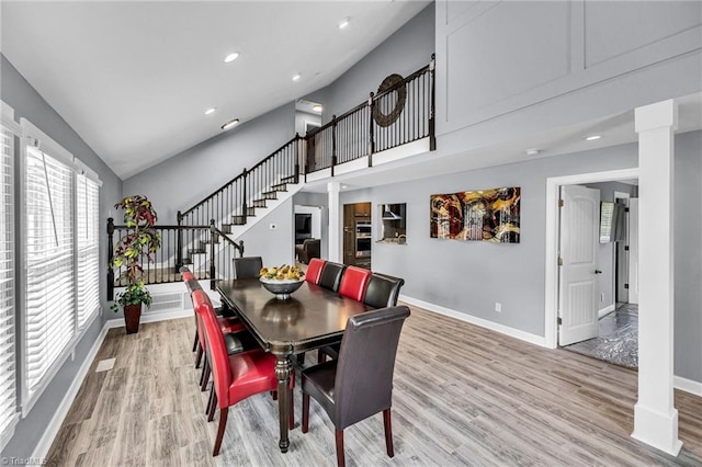 dining room with high vaulted ceiling and light hardwood / wood-style floors