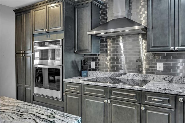 kitchen featuring black electric stovetop, wall chimney range hood, backsplash, and double oven