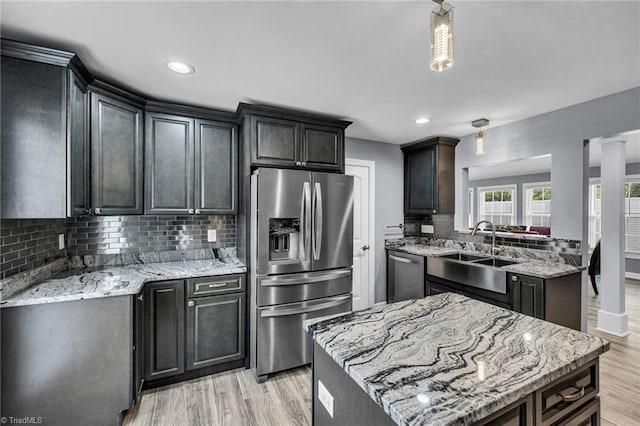 kitchen featuring light stone counters, stainless steel appliances, sink, and a kitchen island