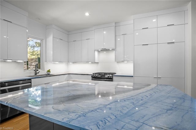 kitchen featuring dishwasher, sink, light stone counters, white cabinets, and black range with gas cooktop