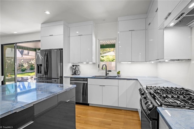 kitchen featuring appliances with stainless steel finishes, white cabinets, sink, and ventilation hood